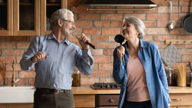 istock Overjoyed older senior couple having fun sing songs at kitchen 1311595000