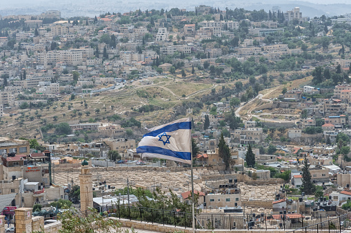 The national flag of Israel on the Jewish Cemetery background. Israel landmarks