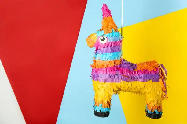 Photo of llama shaped pinata hanging on color background. Space for text