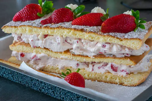 Delicious strawberry cream cake baked with biscuit dough topped with fresh strawberries and served isolated on a table