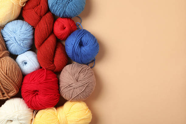 istock Soft woolen yarns on beige background, flat lay. Space for text 1311601536