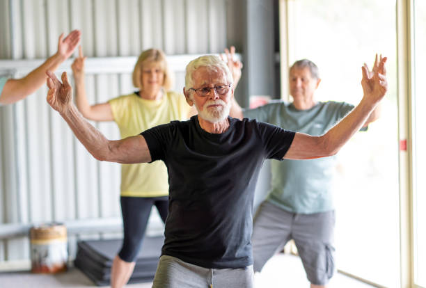 Group of seniors in Tai Chi class exercising in an active retirement lifestyle. Mental and physical health benefits of exercise and fitness in elderly people. Senior health care and wellbeing concept. stock photo