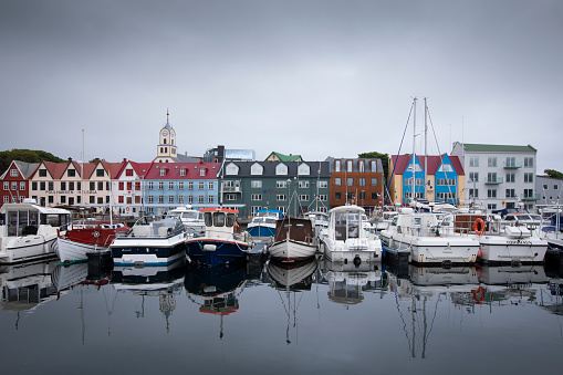 Colorful houses and boats at the harbour of the capital Torshavn, clouds in sky, Faroe Islands