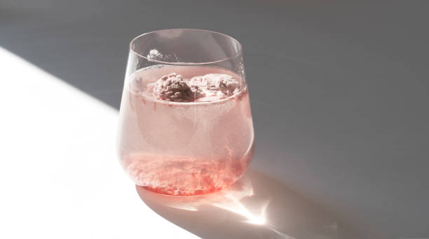 Glass of natural strawberry collagen protein powder in glass of water for skin regeneration. Trendy food additives for young skin. Health and beauty care concept. Natural sunlight. Glass of natural strawberry collagen protein powder in glass of water for skin regeneration. Trendy food additives. White background with sunlight and deep shadow of glass. Hard sunlight. environmental regeneration photos stock pictures, royalty-free photos & images