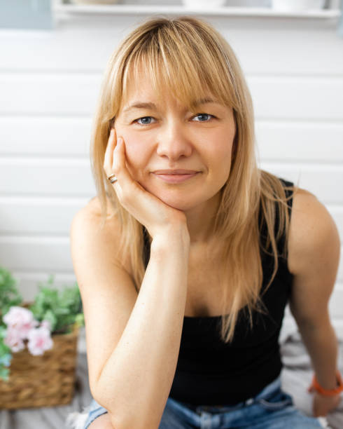 retrato de primer plano de rubia, con bang, mujer diseñadora de paisajes de 40-42 años, mira a la cámara, mano debajo de la barbilla, sin maquillaje, sonrisa en la cara - 35 40 years fotografías e imágenes de stock