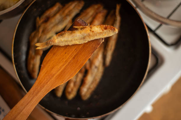 Mallotus villosus - marine ray-finned fish of the smelt family, capelin fried in a pan in corn flour, simple homemade food fried fish, simple homemade food concept, home cooking