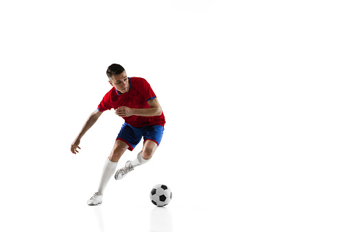 Center forward. Young Caucasian man, male soccer football player in red blue uniform isolated on white background. Action, dynamic. Concept of active life, team game, energy, sport. Copy space for ad.
