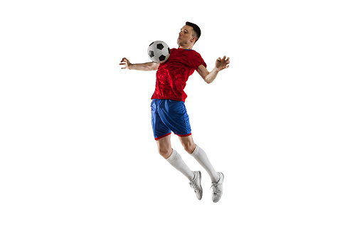 High jump. Young Caucasian man, male soccer football player in red blue uniform isolated on white background. Action, dynamic. Concept of active life, team game, energy, sport. Copy space for ad.