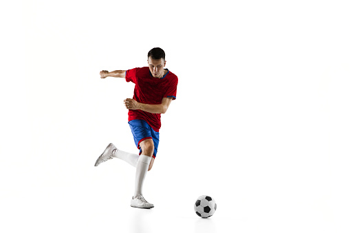 Young Caucasian man, male soccer football player in red blue uniform training isolated on white background. Action, dynamic. Concept of active life, team game, energy, sport. Copy space for ad.