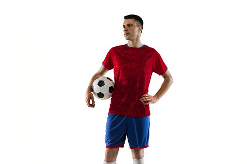 Full length of aged 18-19 years old with black hair generation z male soccer player running in front of white background who is in concentration and holding soccer ball and playing soccer - sport and using sports ball