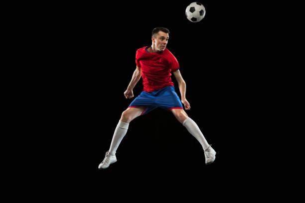 istock Young Caucasian soccer football player practicing isolated on black background. 1311615886