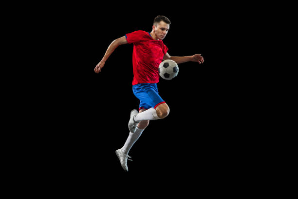 istock Young Caucasian soccer football player practicing isolated on black background. 1311615893