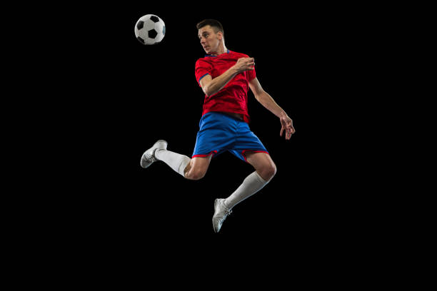 istock Young Caucasian soccer football player practicing isolated on black background. 1311615899
