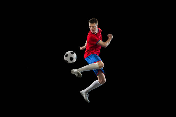 istock Young Caucasian soccer football player practicing isolated on black background. 1311615904