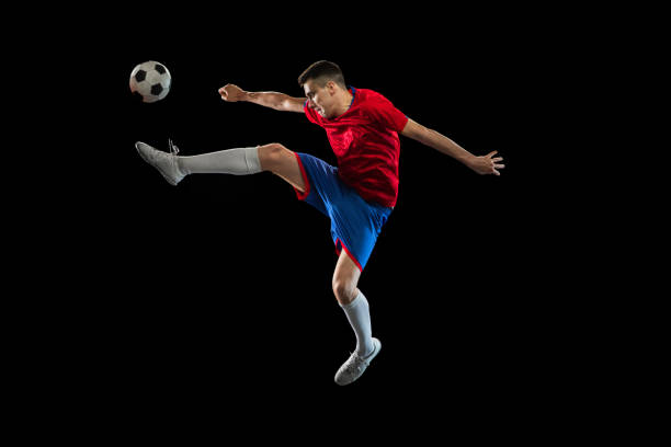 istock Young Caucasian soccer football player practicing isolated on black background. 1311615905