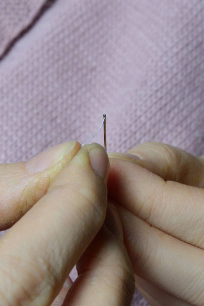 istock female workers' hands sew a wooden button to a jacket. close-up. 1311617196