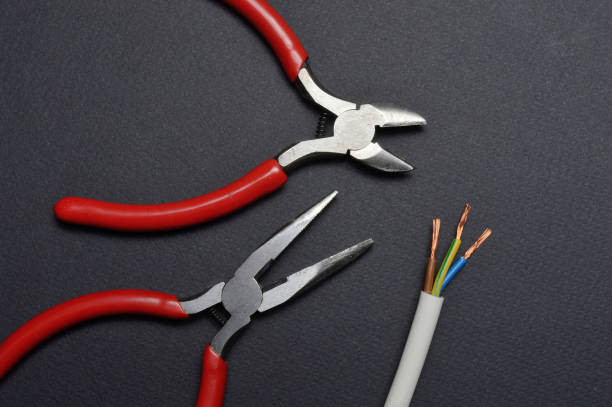 istock wire cutters are in place with a stripped three-core wire. dark background. 1311617367