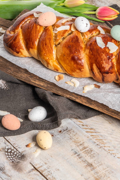 istock Portuguese traditional Easter cake. Folar with eggs on easter table. Blossom tulips, colorful painted eggs and feathers 1311617634