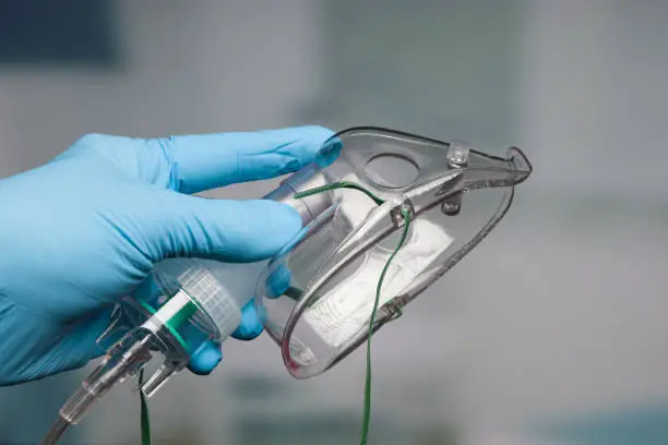 Photo of Doctor's hand with disposable oxygen mask for breathing support