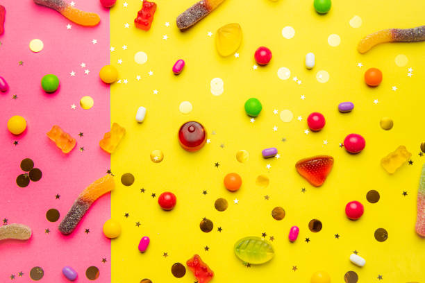 istock Candy assorted layout. Layout with candy on a yellow-pink background. Chewy marmalade and small caramels . Bright background. Sweets for every taste. An article about sweets. 1311619865