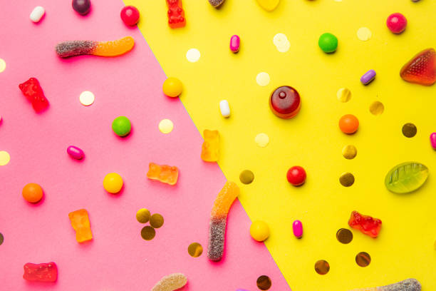 istock Candy assorted layout. Layout with candy on a yellow-pink background. Chewy marmalade and small caramels . Bright background. Sweets for every taste. An article about sweets. 1311619877