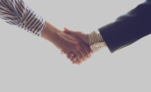 Picture of two business people shaking hands on gray background