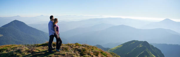 istock Loving couple standing on grassy hill in mountains. 1311621069