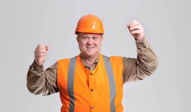 istock happy construction worker in hard hat with raised hand up on grey studio background, cheerful fat engineer 1311622780