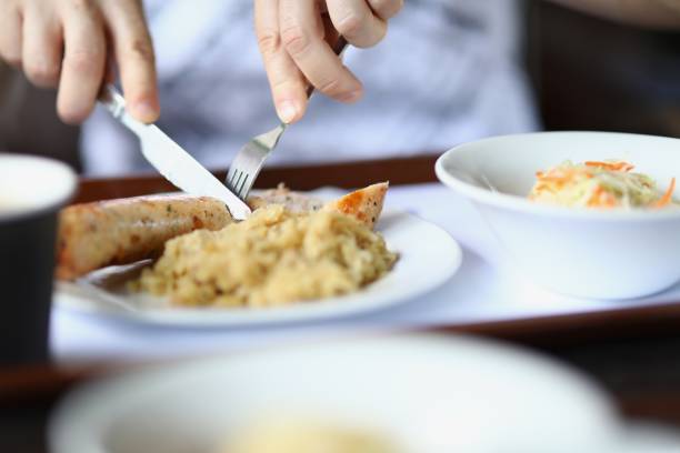 istock Man eating fried sausage with knife and fork 1311623513