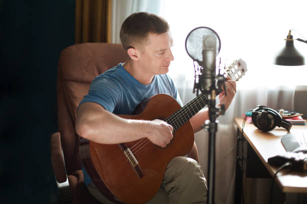 istock man playing guitar  to microphone in home recording studio, copy space 1311623603