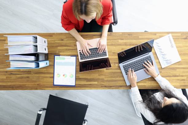 istock Female colleagues working on laptop in office top view 1311624855