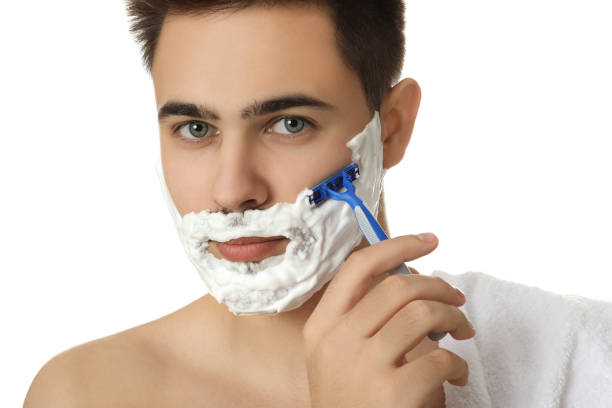 istock Handsome young man shaving with razor on white background, closeup 1311625167