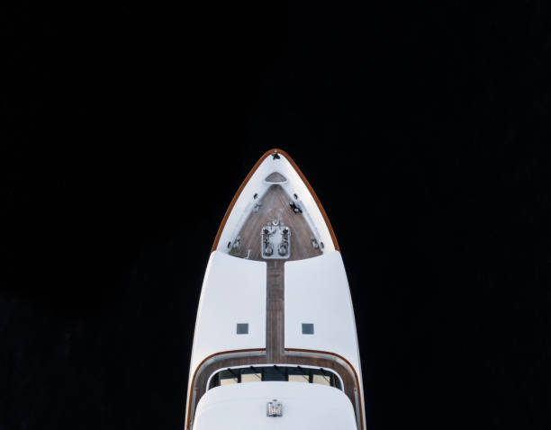 High angle aerial bird's eye partial view of the bow of a long white luxury yacht with wooden deck in dark blue waters shortly after sunset in Sydney, Australia with a lot of copy space. High angle aerial bird's eye partial view of the bow of a long white luxury yacht with wooden deck in dark blue waters shortly after sunset in Sydney, Australia with a lot of copy space. ships bow photos stock pictures, royalty-free photos & images