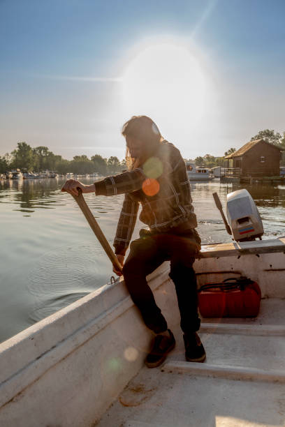 istock Man in old white boat is rowing in sunrise 1311629191