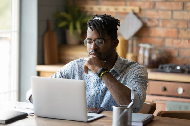 istock Focused black male read web search result on laptop screen 1311634178