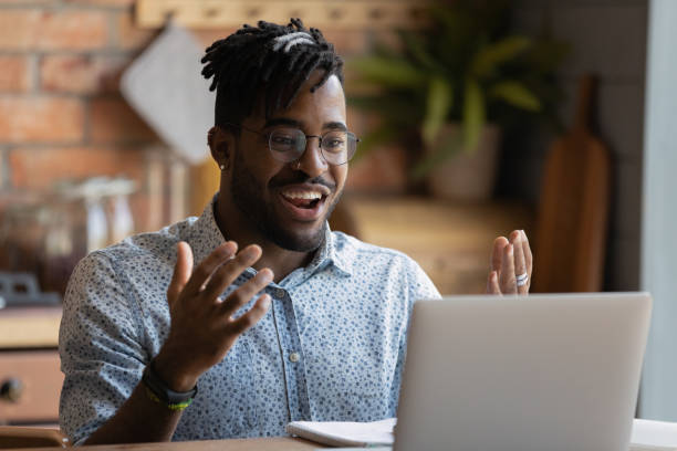 istock Overjoyed young black guy splash hands looking at laptop screen 1311634201