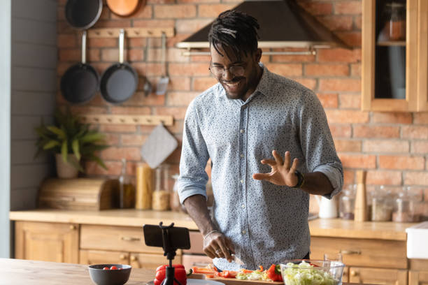 istock Young african guy broadcast live preparing dish on domestic kitchen 1311634277