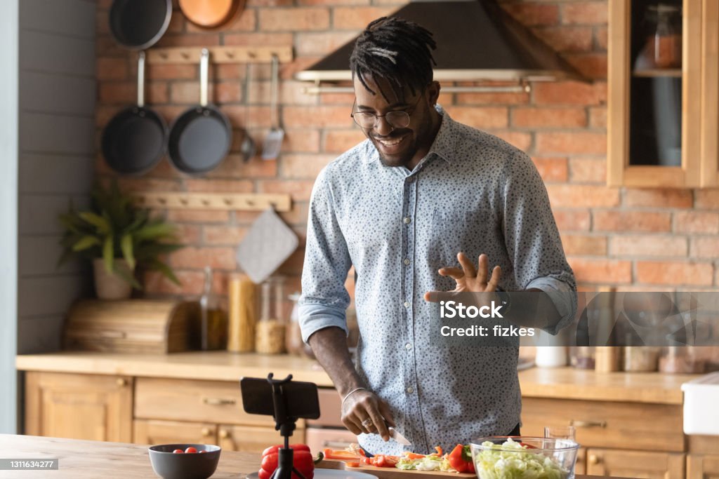 Young african guy broadcast live preparing dish on domestic kitchen Cooking master class. Confident black man vlogger shoot tutorial teach audience to make healthy food. Young african guy capable cook broadcast live preparing national cuisine dish on domestic kitchen Cooking Stock Photo