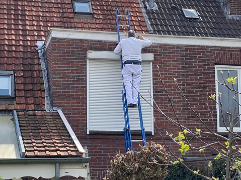 Brunssum, the Netherlands, - April 01, 2021. House painter in action on a sunny april day.