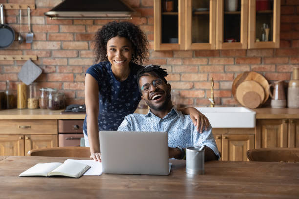 istock Happy modern day african family couple using laptop at kitchen 1311638334