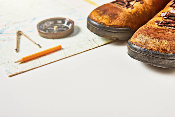 worn, battered old hiking boots with map, compass, dividers and pencil, with copy space - compass hiking map hiking boot imagens e fotografias de stock