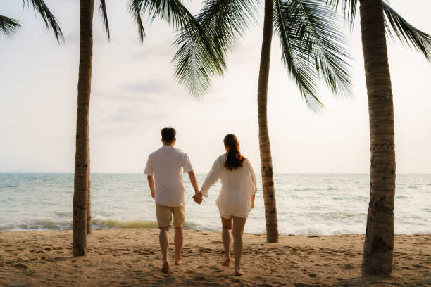 istock Asian couple is running and holding hands on a beachfront beach sea with coconut trees while on vacation in the summer in Thailand. 1311642522