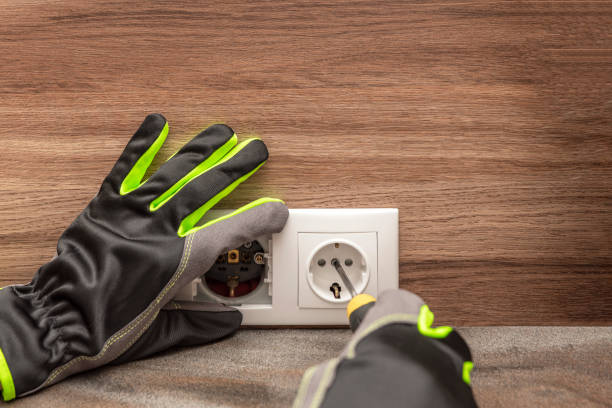 installing electrical outlets. the electrician installs a decorative frame on the electrical outlets. screwdriver in the hands of a master installing a socket with gloves - art installation imagens e fotografias de stock