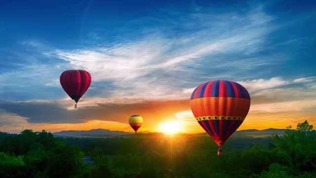 Aerial view of colorful hot air balloons flying over at summer sunset.