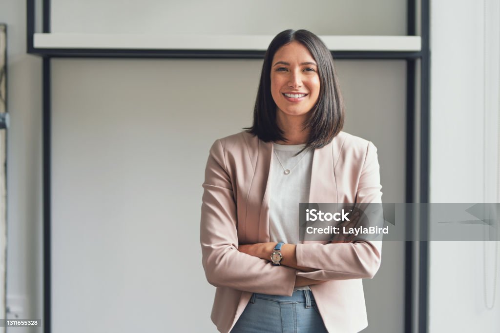 I'm the best asset in my business Cropped portrait of an attractive young businesswoman standing alone in her office with her arms folded during the day Women Stock Photo