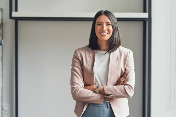 I'm the best asset in my business Cropped portrait of an attractive young businesswoman standing alone in her office with her arms folded during the day portrait stock pictures, royalty-free photos & images