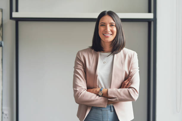 I'm the best asset in my business Cropped portrait of an attractive young businesswoman standing alone in her office with her arms folded during the day smiling stock pictures, royalty-free photos & images