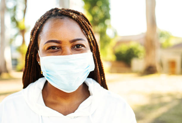 istock Young woman smiling from under a face mask outside in summer 1311659785