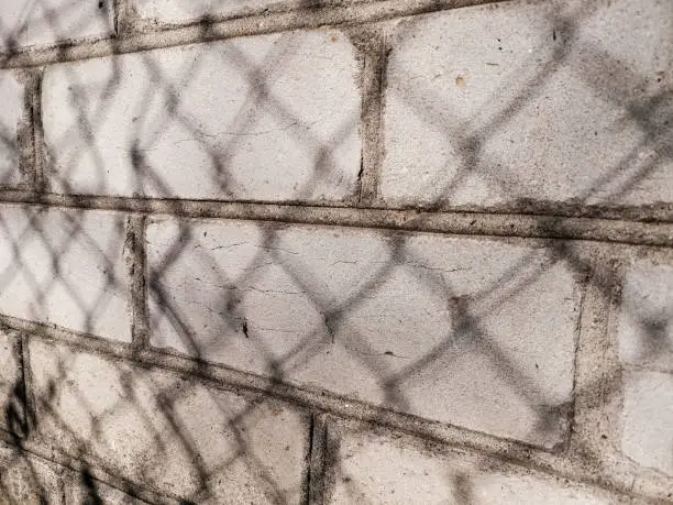 Photo of Shadow from the netting chain-link on a brick wall in the setting sun (light photo)