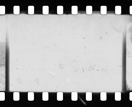 Dusty and grungy 35mm film texture or surface. Perforated scratched camera film isolated on white background.